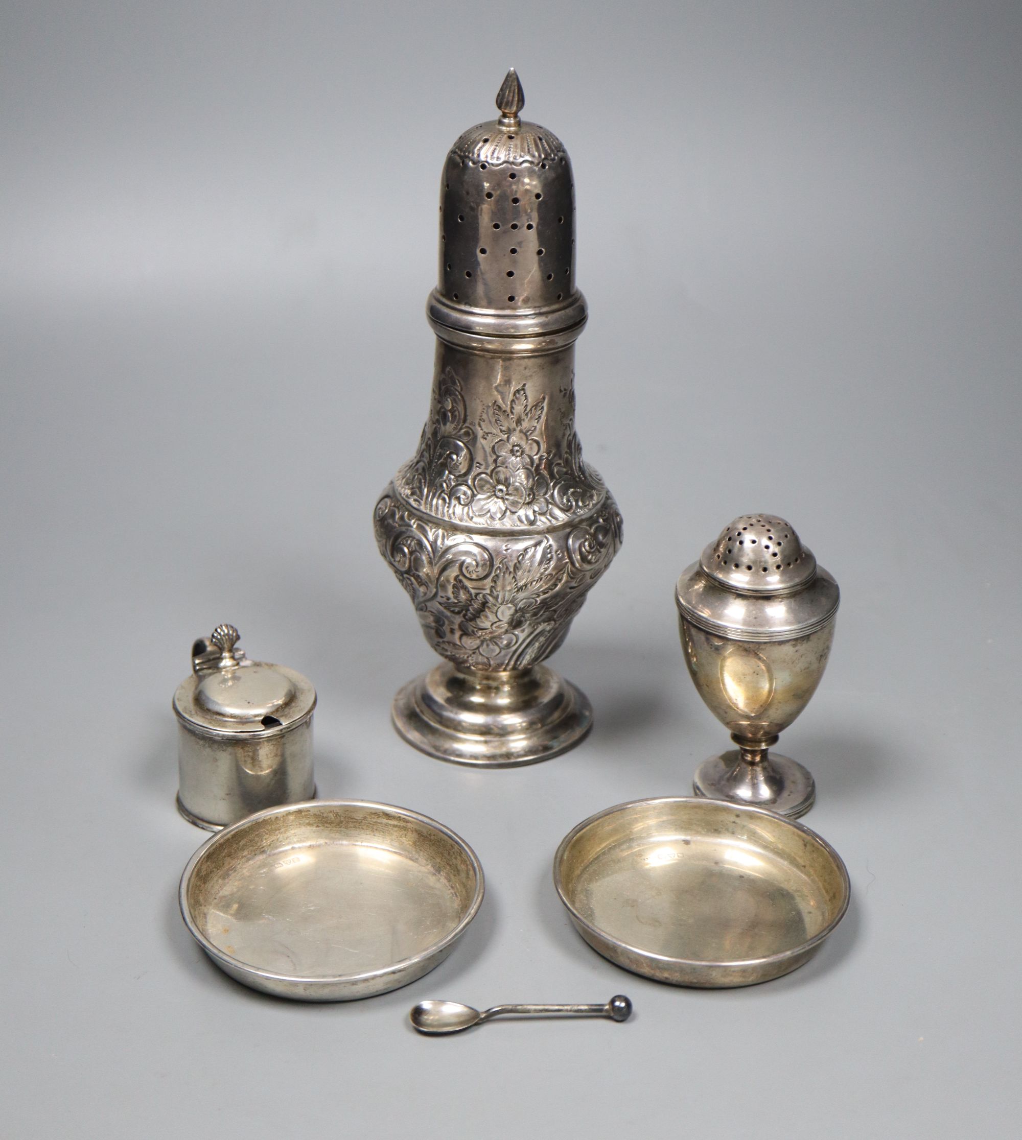 An Edwardian embossed silver sugar caster, 21.2cm, a small Georgian caster, a silver mustard and two circular pin dishes,